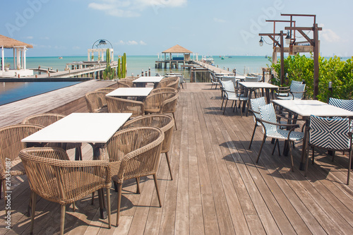 Fototapeta Naklejka Na Ścianę i Meble -  Rows of wooden chair and table locate on terrace of restaurant with seascape in the background.