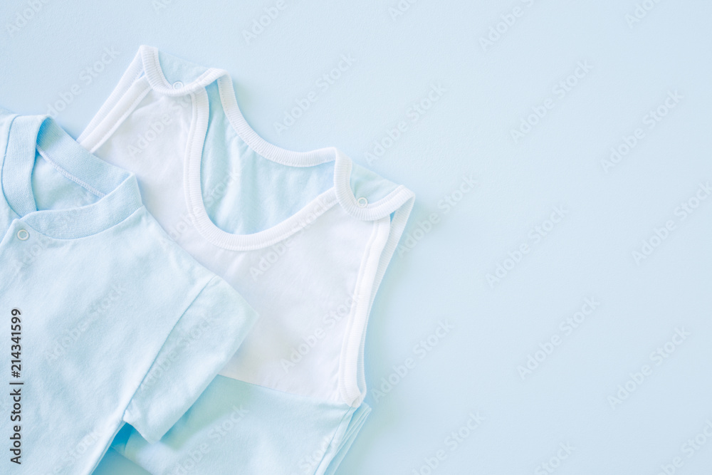 New, light blue bodysuit on the pastel blue table. Baby clothes. Soft colors. Empty place for text or logo. Top view. Flat lay.
