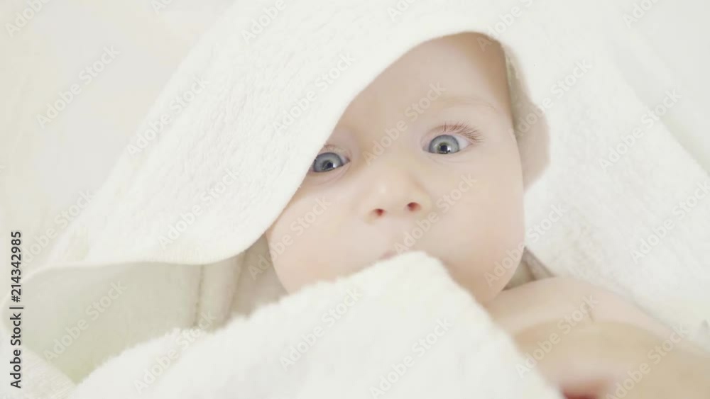 Adorable little baby after bath wrapped in towels, close up portrait with blue eyes irresistible look Adorable little baby after bath wrapped in towels, close up portrait with blue eyes irresistible look