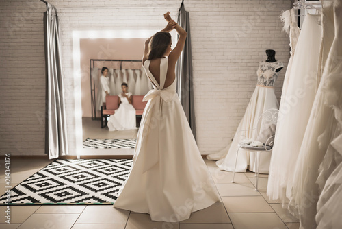 beautiful woman in wedding shop trying on a dress back