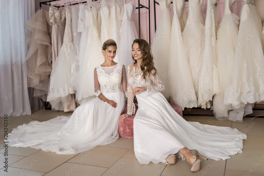 Models in expensive lace dresses posing in wedding salon Models in expensive lace dresses posing in wedding salon