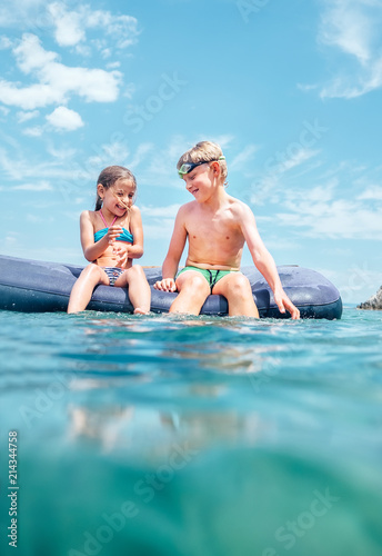 Sister and brother, have fun when swim on inflatable mattress in the sea. Careless childhood time