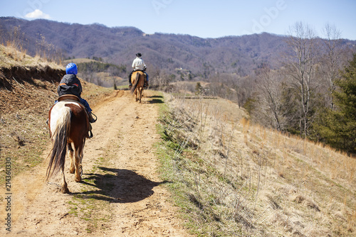 Child and Man Riding Horses on Trail © Katie