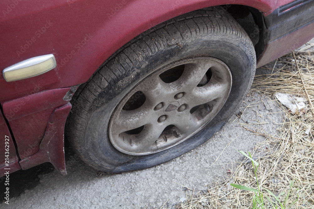 blasted tire on red car needs repair