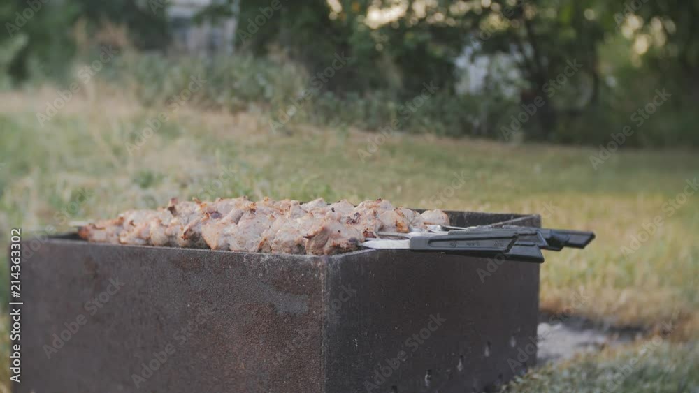 Appetizing shashlik outside. Man cooking. Cooking of pork meat. Barbecue lunch outdoors. Process of cooking pork meat on fire. Shashlik prepared on barbecue grill over charcoal Appetizing shashlik outside. Man cooking. Cooking of pork meat. Barbecue lunch outdoors. Process of cooking pork meat on fire. Shashlik prepared on barbecue grill over charcoal