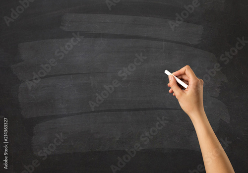 Female hand holding white chalk in front of a blank blackboard photo