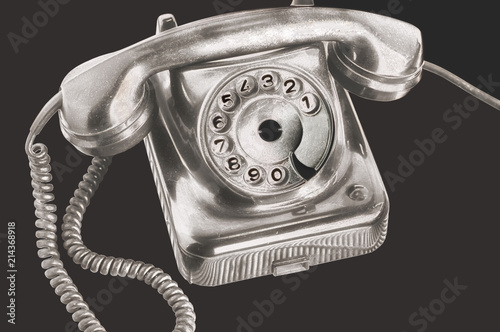 Photography An ancient silver dial disk phone in futuristic processing on isolated black bac