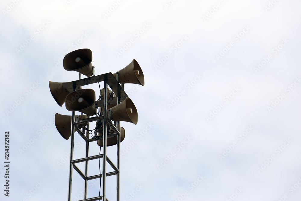Loudspeaker tower for public relations on metal pole isolated in the bright sky. Loudspeaker tower for public relations on metal pole isolated in the bright sky.