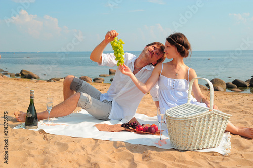 young loving couple in white during a picnic on the beach photo
