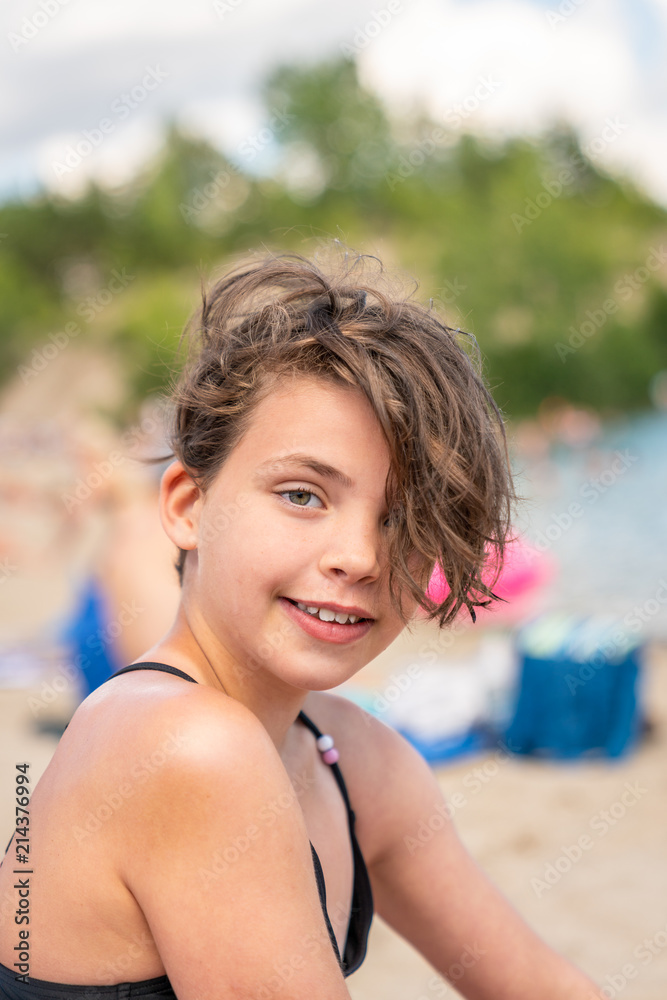 Close up summer portrait of a cute young girl with messy hair on a beach.