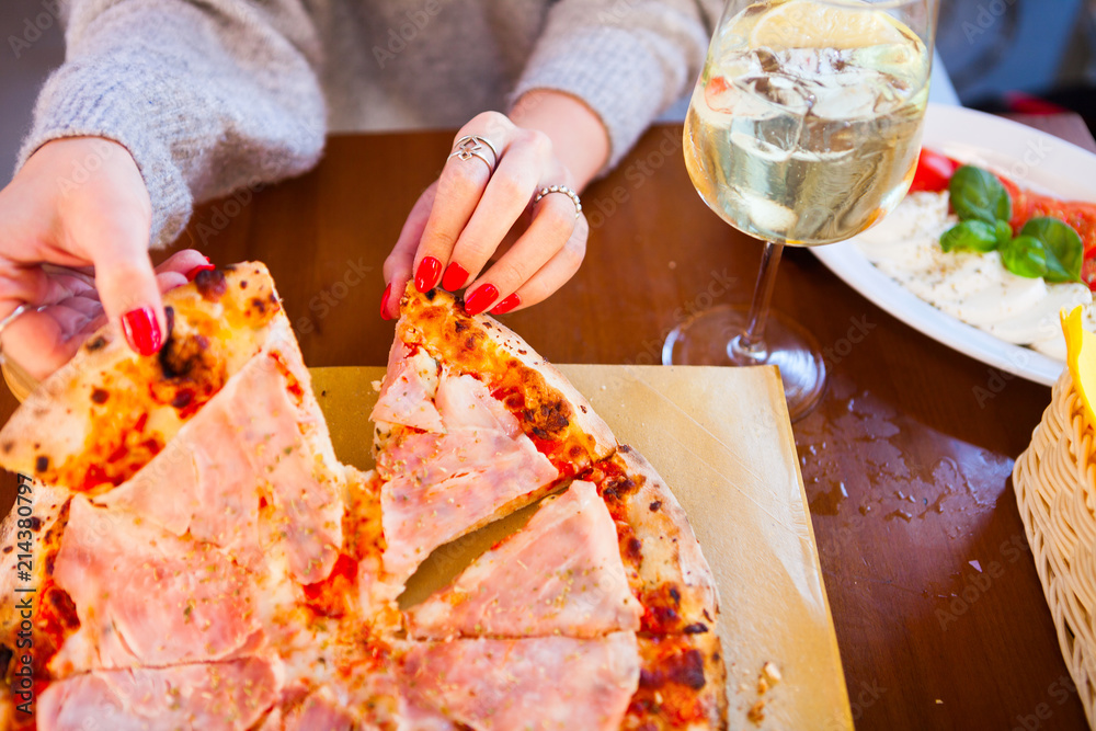 Italian food dinner. Woman eating Pizza with tomato prosciutto mozzarella glass white wine summer outdoor restaurant