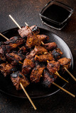 Grilled beef liver on skewers, with teriyaki or soy sauce, yakitori, dark rusty  table copy space top view