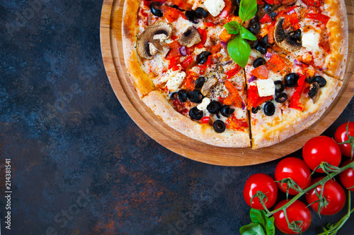 Homemade pizza with tomatoes, mozzarella and basil. Top view with copy space on dark stone table. photo