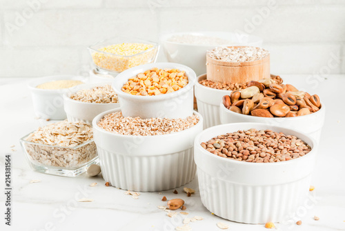Selection various types cereal grains groats  in different bowl on white marble background, copy space