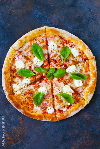 Homemade pizza with tomatoes, mozzarella and basil. Top view with copy space on dark stone table. photo