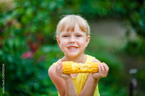 Foto The cheerful girl eats corn on a farm.