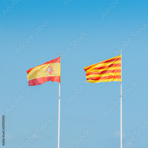 Catalonian and Spanish flags flying on a mast against a blue sky photo