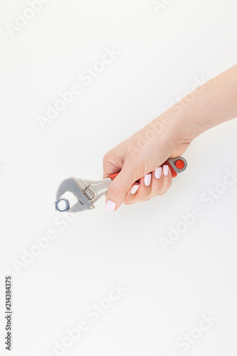 Female hand holding spanner on white background