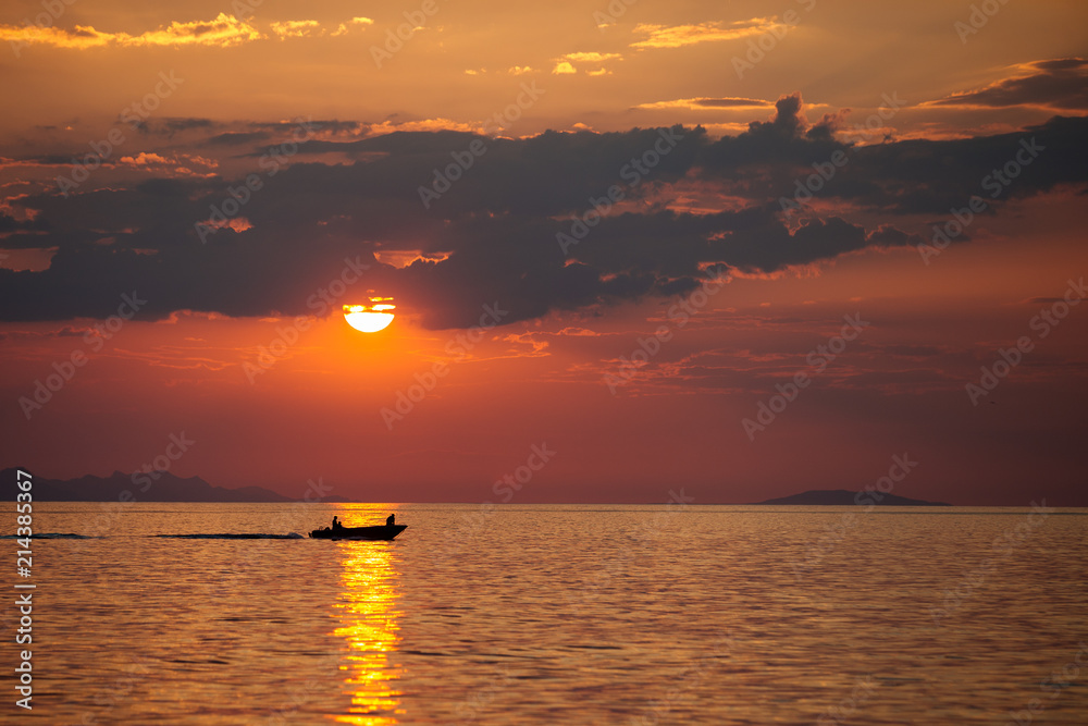 Fishing boat passes the sun path reflection in the sea on sunrise