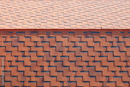 The texture of the roof with bituminous coating. Rough bituminous mosaic of red and brown flowers. Waterproof roofing