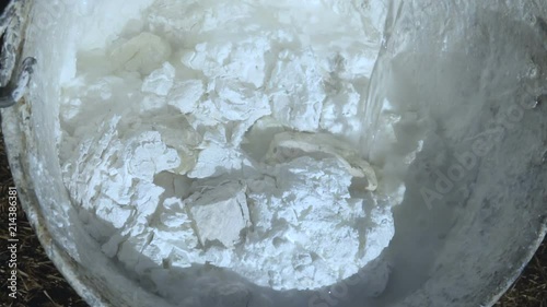 Chemical reaction. Lime slaking in a stainless steel bucket. It is used for whitewashing trees.