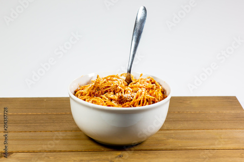 Spaghetti Bolognese in a deep white bowl on the wooden kitchen table waiting to be eaten