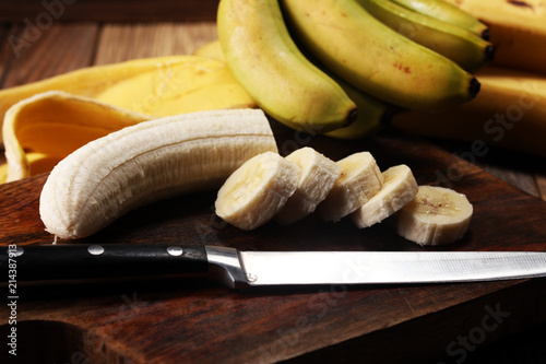 A banch of bananas and a sliced banana over a table.