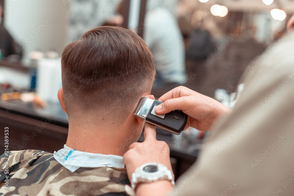 Barber in shear hair electric car to young guy hipper for