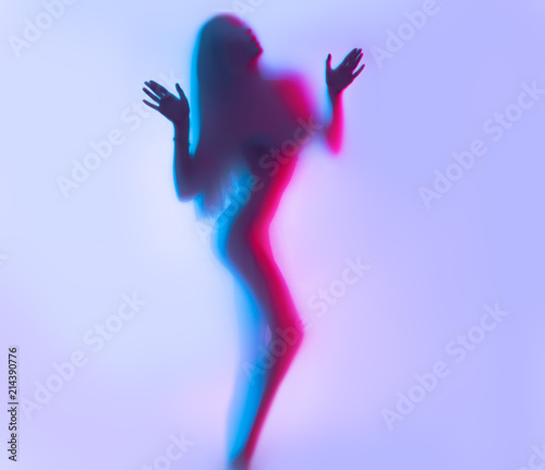 Beauty model girl dancing silhouette. Beautiful sexy young woman with perfect slim body dance in uv light photo