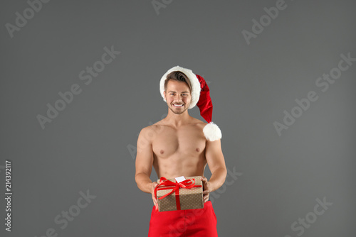 Shirtless sexy young Santa Claus with gift on color background photo