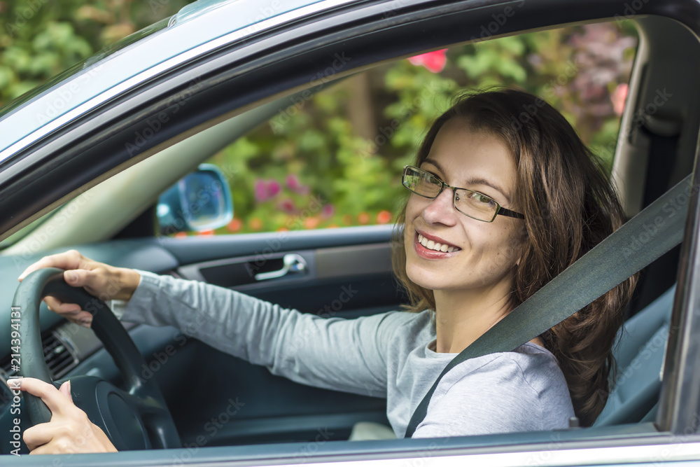 A happy young woman is sitting at the wheel of a car. Girl driver. A happy young woman is sitting at the wheel of a car. Girl driver.