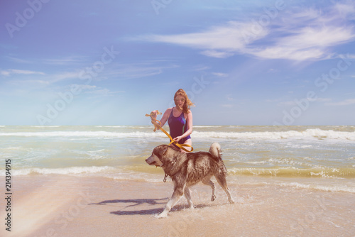 Woman smile during walk with husky at beach