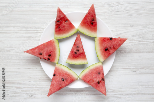 Creative layout of chopped watermelon on white plate over white wooden background, top view. Flat lay, overhead.