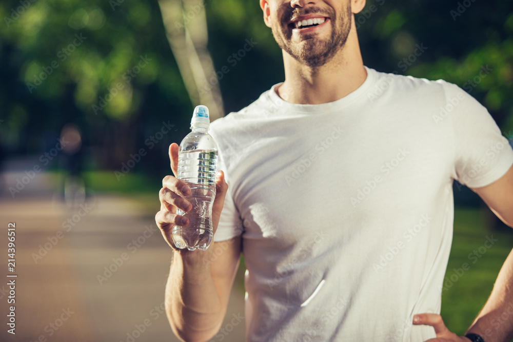 My choice. Close up of male hand holding bottle of liquid. Young guy is happily demonstrating it outdoors My choice. Close up of male hand holding bottle of liquid. Young guy is happily demonstrating it outdoors