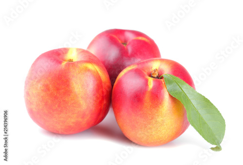 A large ripe fresh nectarine with a leaf on a white isolated background