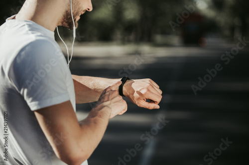 Εκτύπωση καμβά Focus on smiling man standing and looking at fitness tracker on wrist
