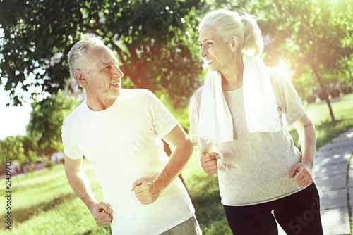 Energetic pensioners. Happy energetic elderly couple spending time together while running in a beautiful park