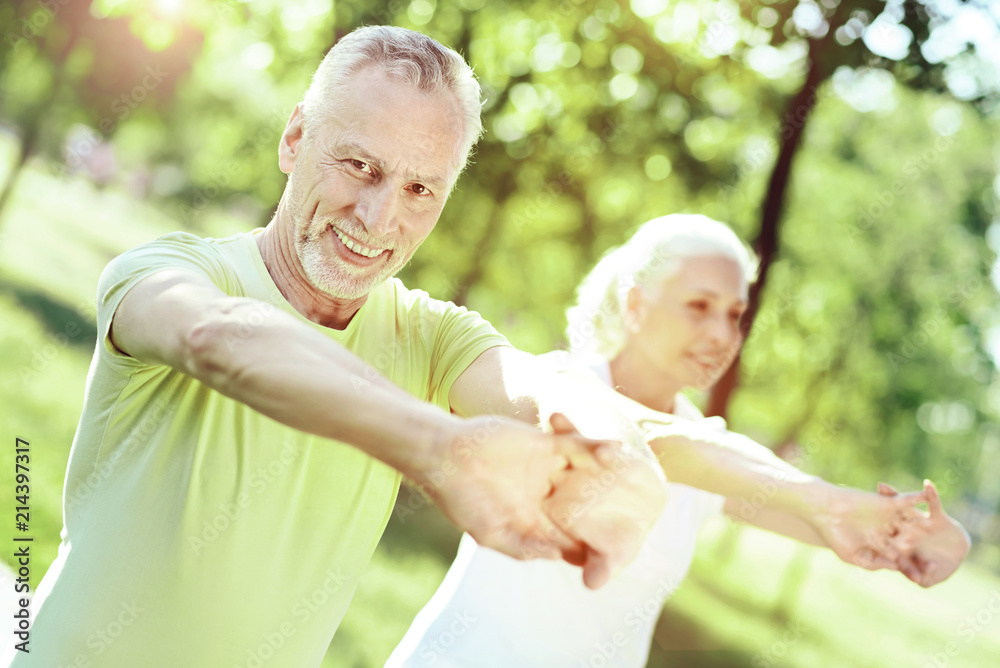 Kind smile. Positive emotions of a kind friendly senior man exercising in a park Kind smile. Positive emotions of a kind friendly senior man exercising in a park