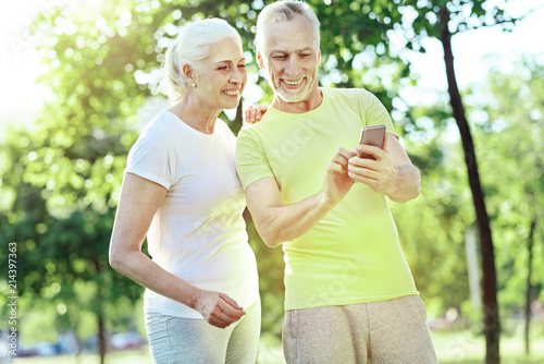 Look here. Cheerful progressive aged man showing a modern smartphone to his curious wife