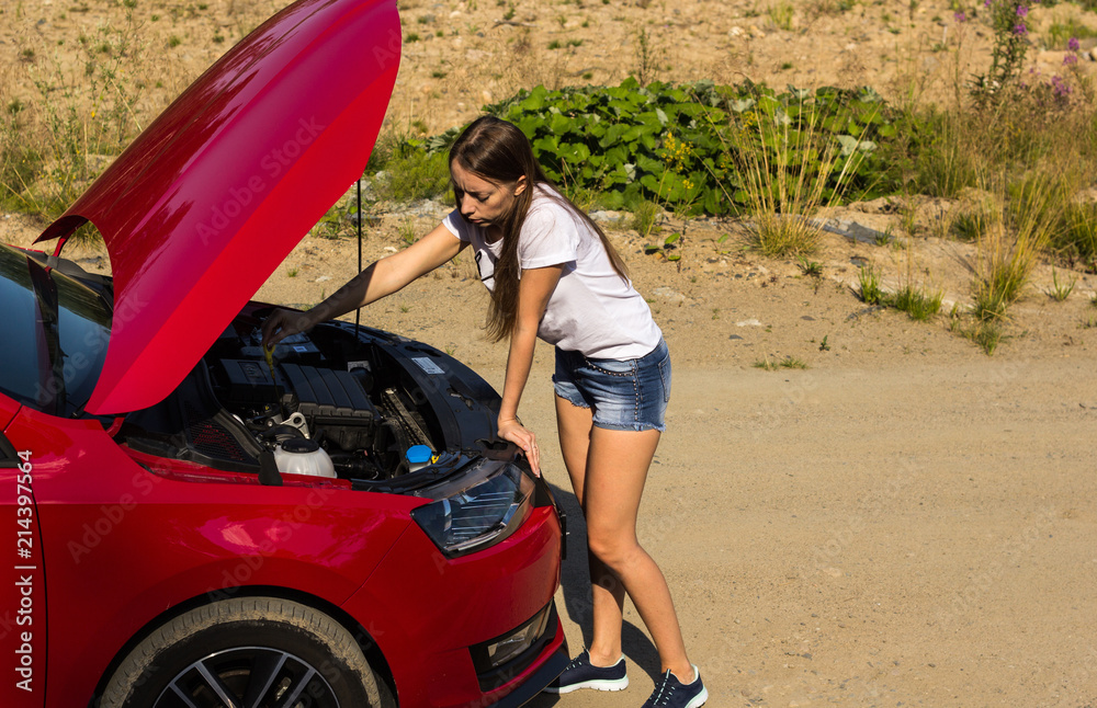A broken car on the road, the girl checks the oil level A broken car on the road, the girl checks the oil level