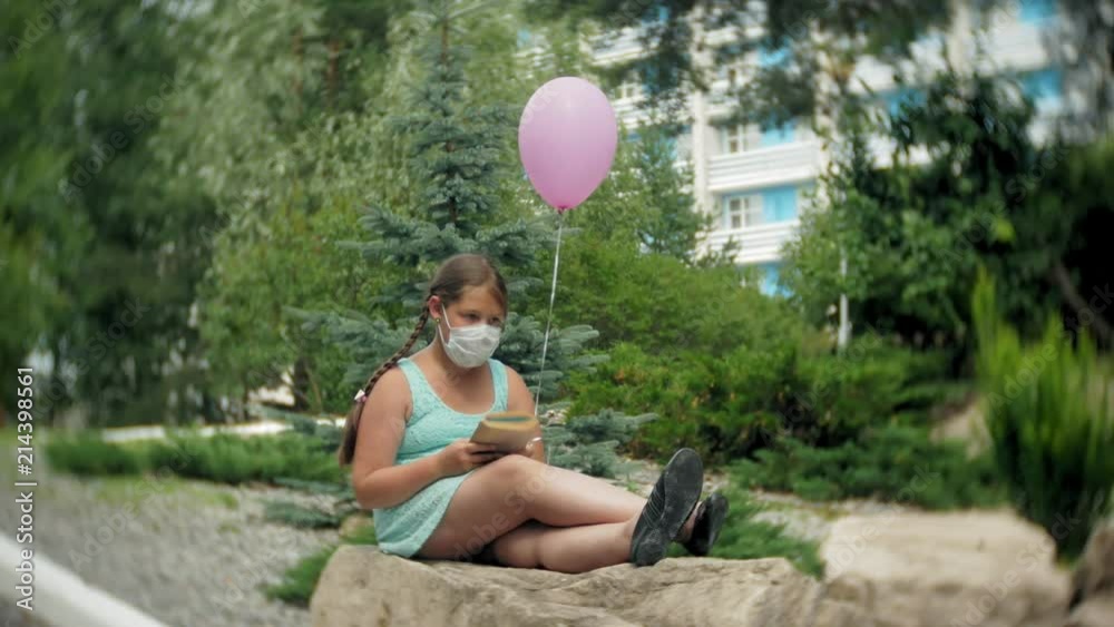 Cute girl in a respirator reading a book in the park Cute girl in a respirator reading a book in the park