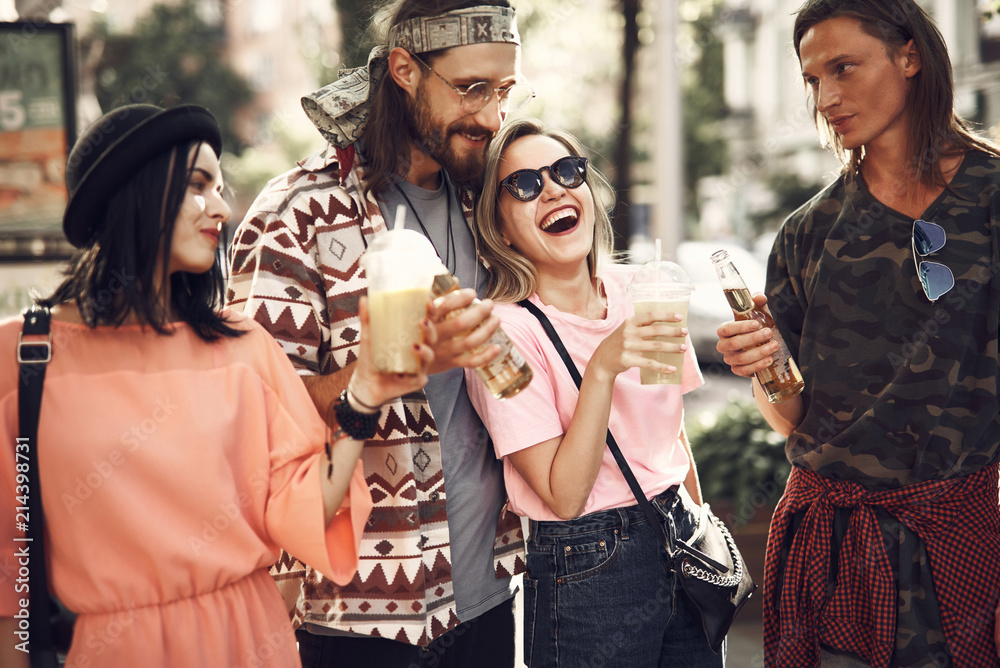 Laughing females and cheerful men drinking delicious liquid while going outdoor. They talking together Laughing females and cheerful men drinking delicious liquid while going outdoor. They talking together