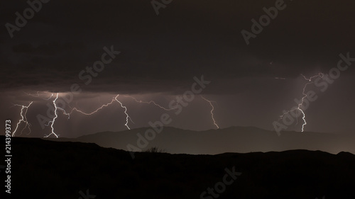 Lightning flickering over distant mountains at night