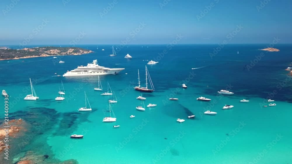 Aerial view of some yachts and a big luxury yacht on an emerald and transparent Mediterranean sea. Gulf of the Great Pevero, Emerard coast, Sardinia, Italy.