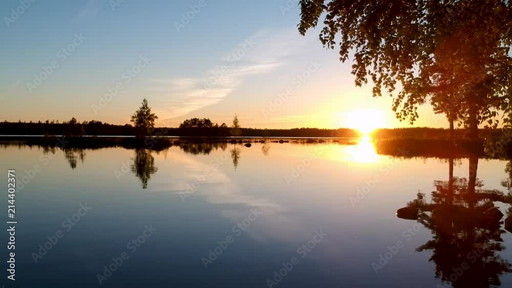 Drone flying low under a tree over a lake in a forest during sunset in Sweden Drone flying low under a tree over a lake in a forest during sunset in Sweden