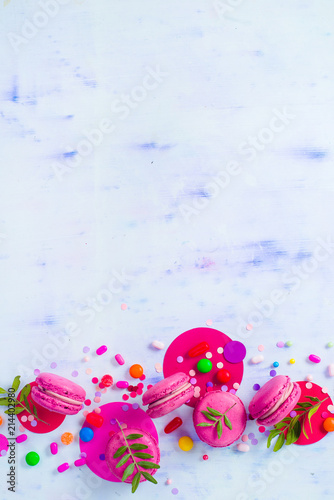 Macaroon cookies on a colorful background with confetti. Vibrant party concept with copy space. Pink and purple palette flat lay.