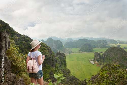 woman tourist with backpack enjoying valley view from top of a mountain