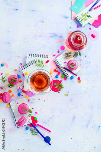 Tea party with a tiny glass teapot, candies, and confetti on a light background with copy space. Pink and purple palette still life. Vibrant drinks concept