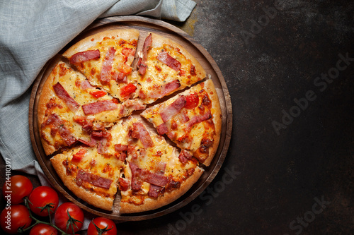 Delicious Italian pizza sliced ham, bacon and cheese with food ingredients on old kitchen table.