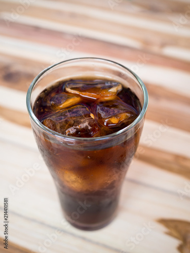 Drink cola with ice in glass on wooden table